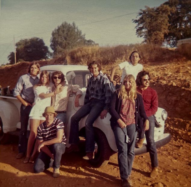 A group of people smiling and posing in front of a parked truck, showcasing camaraderie and a shared moment