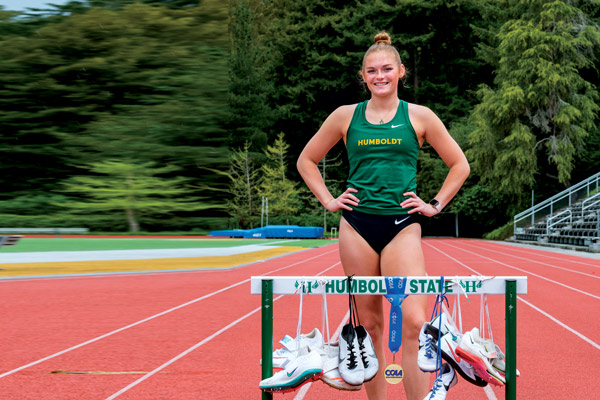 a standing on the track with shoes hanging from a hurdle