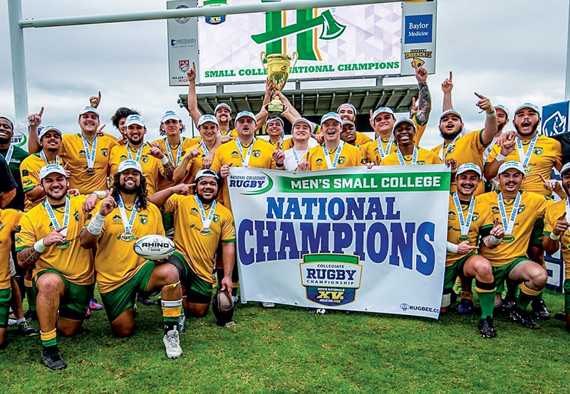 Rugby team sitting in a group holding their trophy