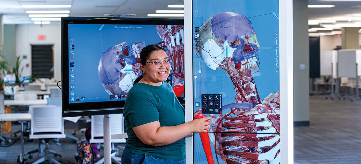 Alum Jaquelinee Salas Haro at a fully segmented, real-human 3D anatomage table at the Library.