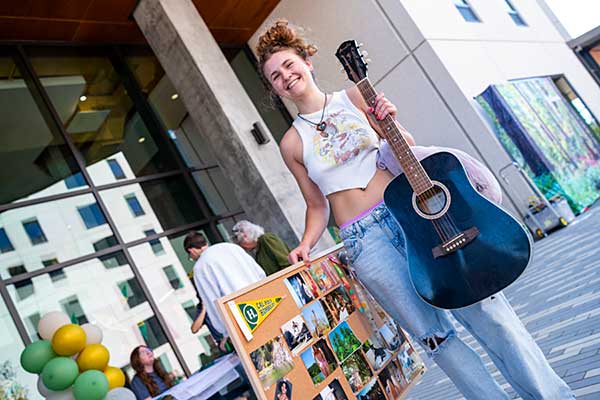 Three young students standing together in front of a modern building, smiling and engaged in conversation